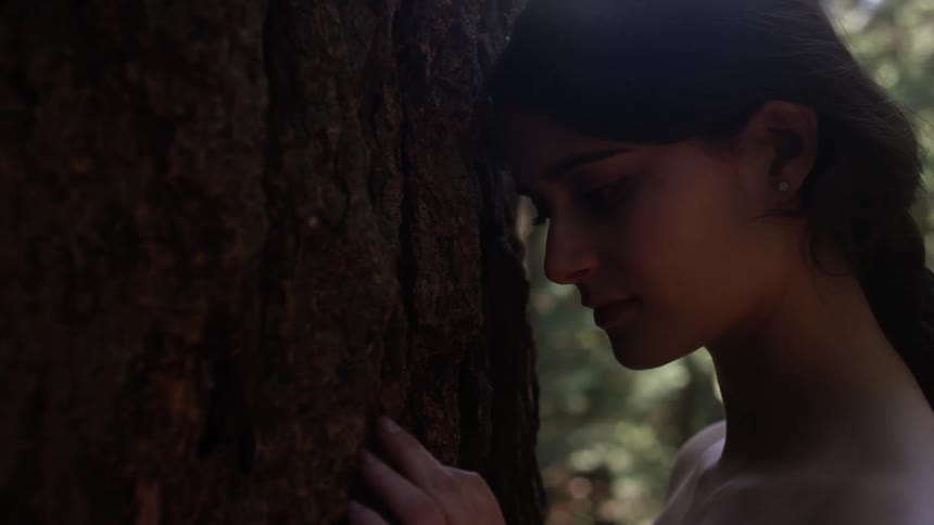 A woman feels the trunk of a tree