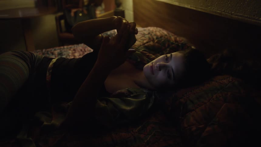 A woman lays in bed while using her phone