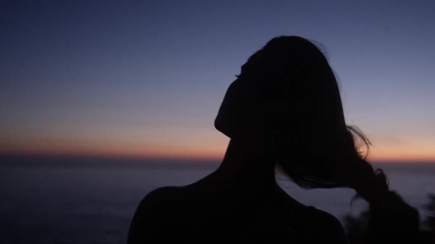 A woman looks out over the setting sun