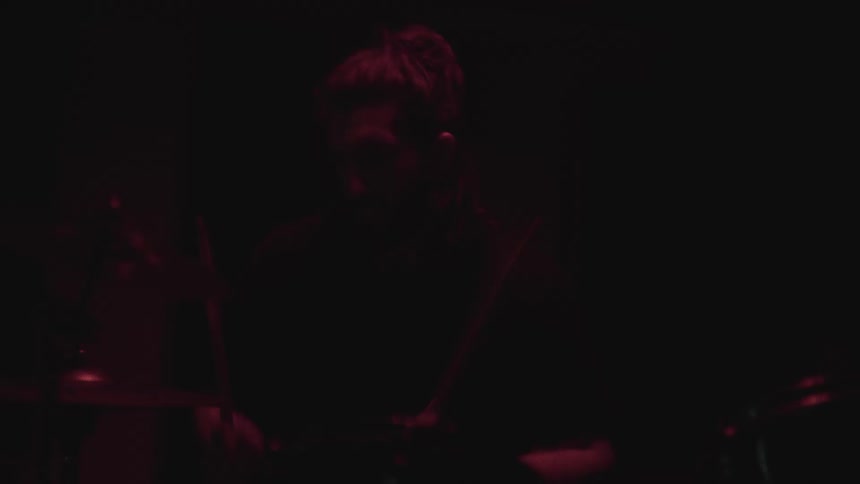 A musician is playing the drums while indoors at night