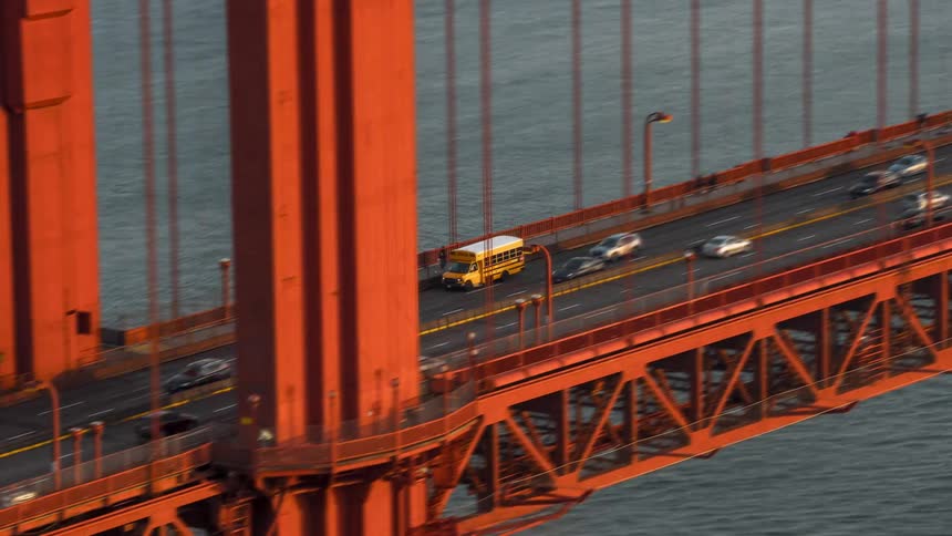 Yellow school bus commuting with other vehicles across golden gate bridge