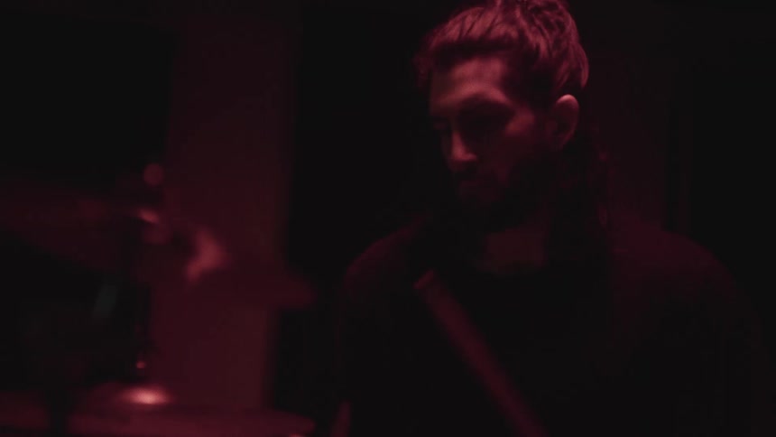 A man is playing the drums in the dark