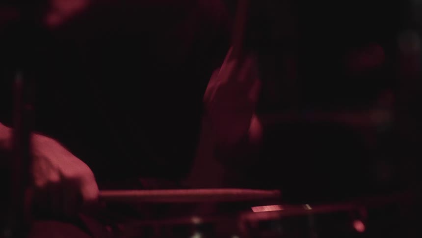A man is playing the drums in the dark