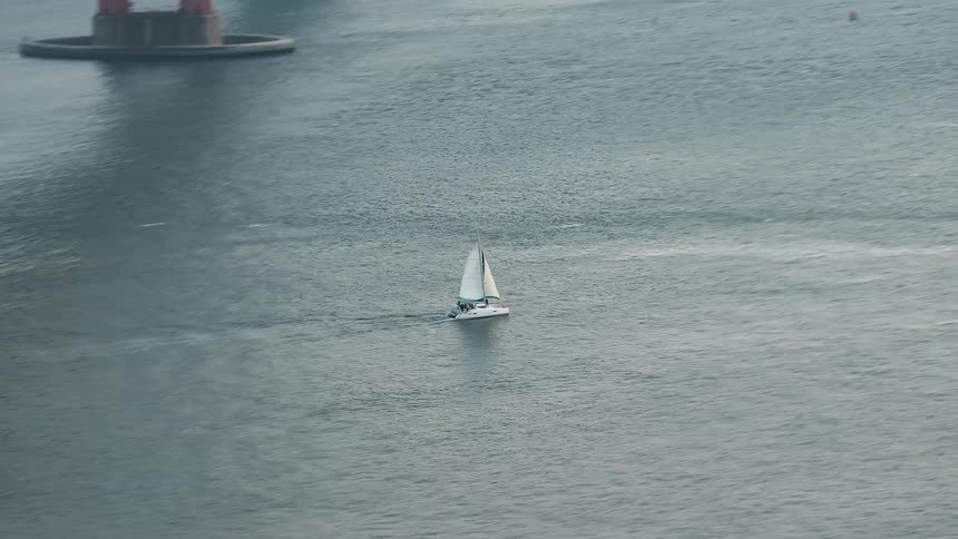 A sailboat is traveling under the bridge