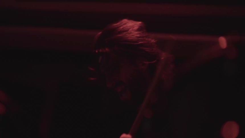 A man is playing the drums aggressively at a fast pace