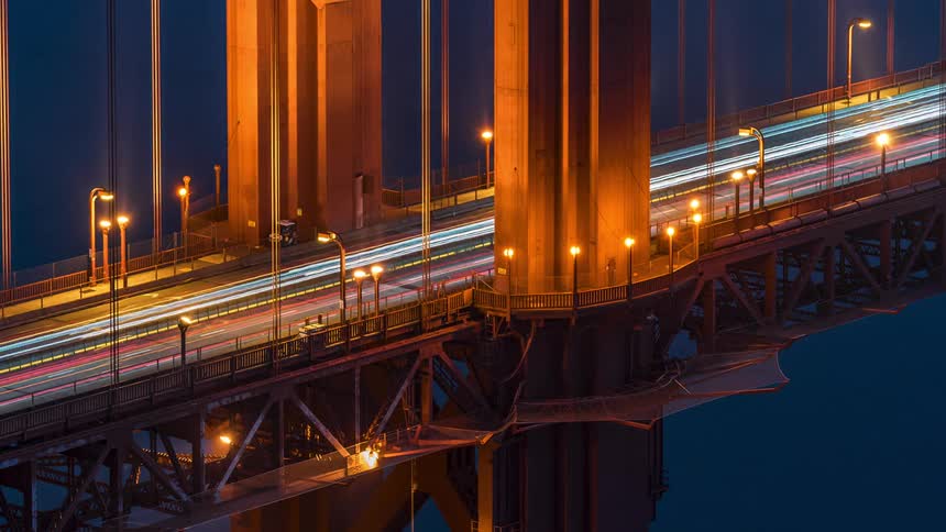 The golden gate bridge at night with blurred streaks of car headlights and lit street lamps along its length