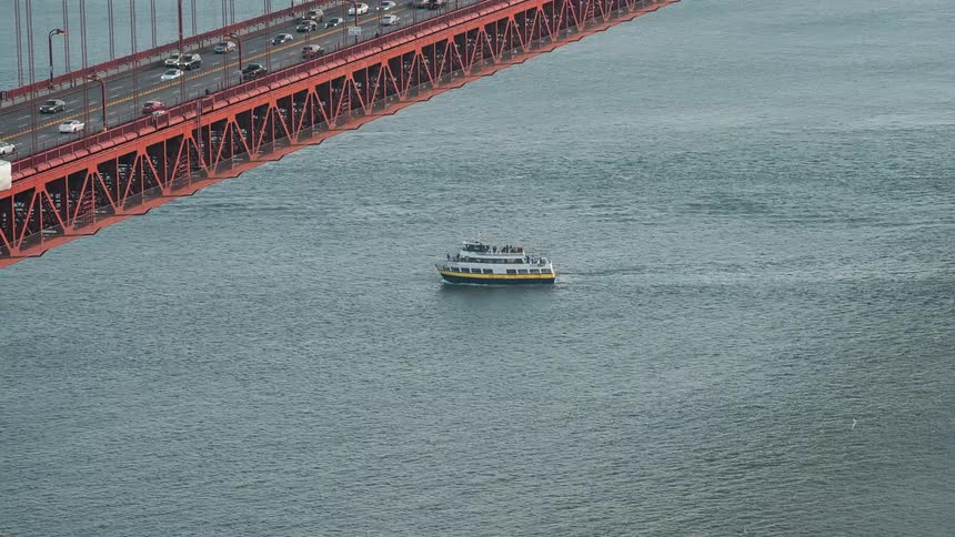 A ship travels under the large bridge