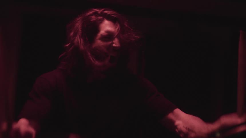 A man is playing the drum instrument aggressively indoors