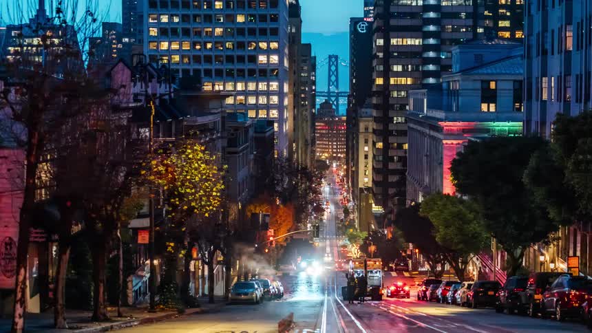 A nighttime scene of traffic in the city with a bridge in the background
