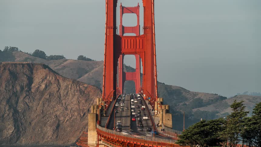 Many cars crossing a bridge in the middle of the mountains