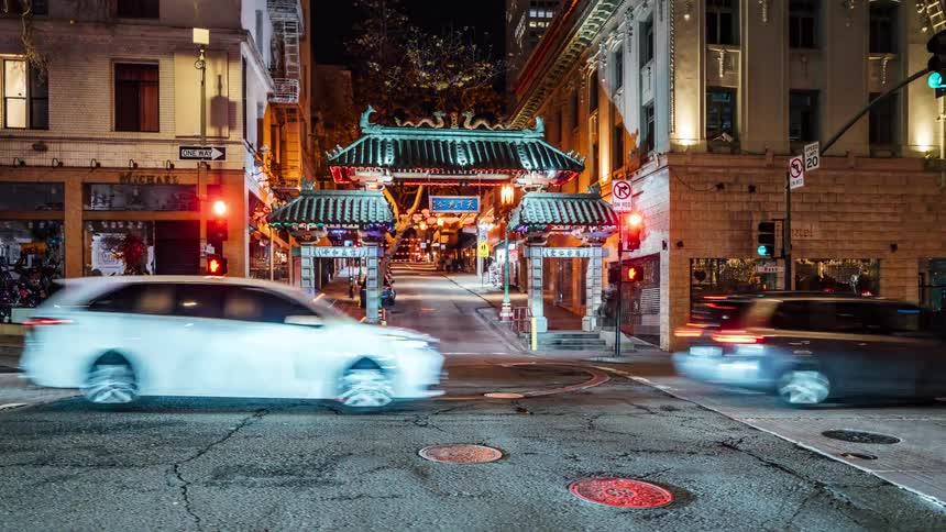 Traffic crosses through an intersection near an asian styled road gateway at night