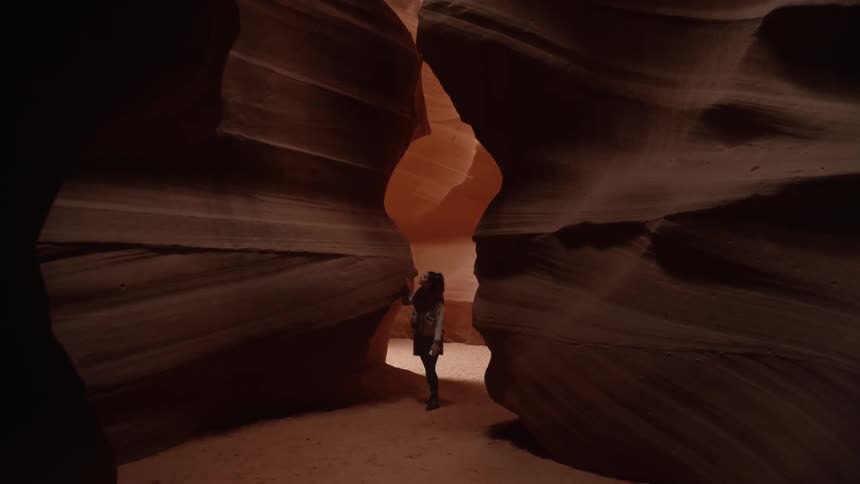 A woman walks through an opening in large rock formations