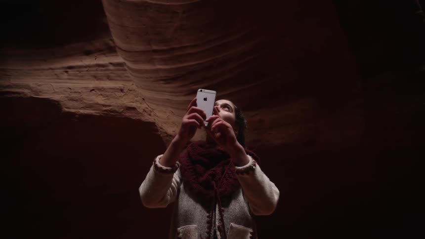 A woman takes photographs with her phone in a canyon