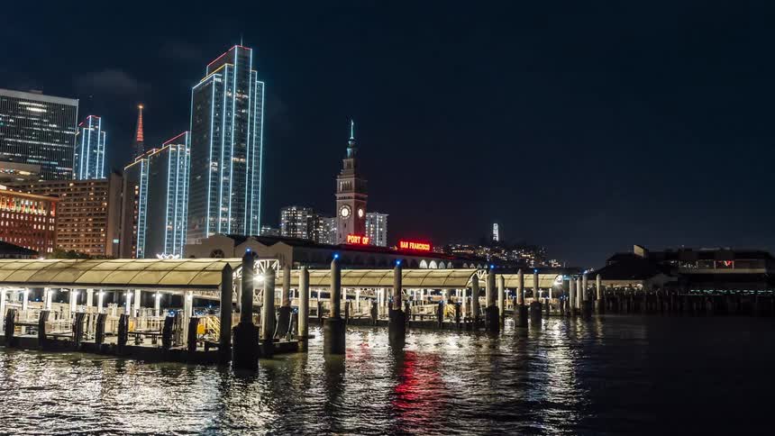 A citys docks seen at night in front of neonlit skyscrapers
