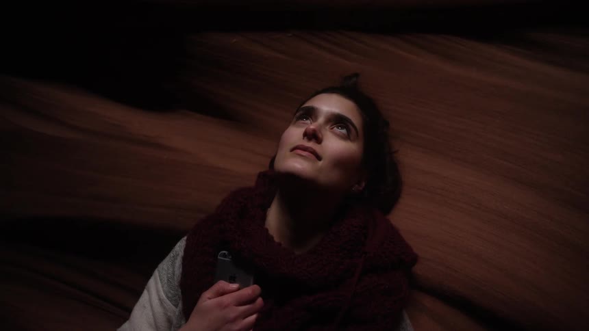 A woman is looking up in a dark cavern