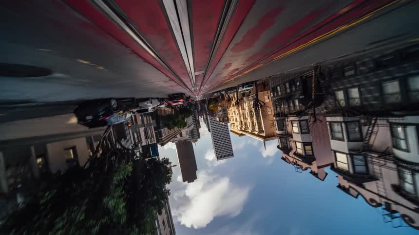 Speeding down a street in san francisco lined with buildings and tram tracks under a blue partly cloudy sky