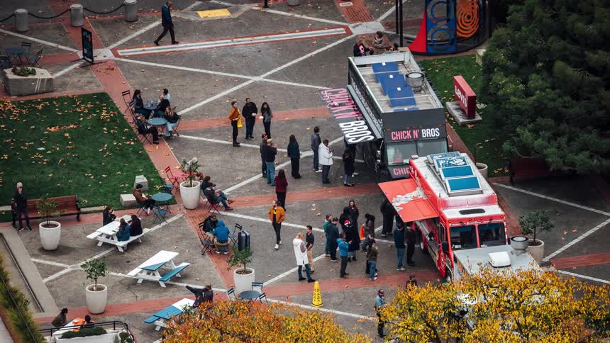 People are lined up and buying food from food trucks