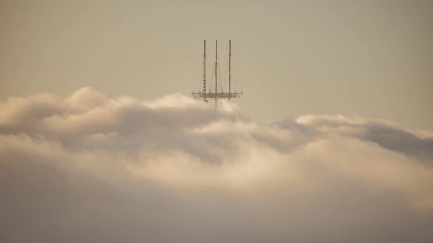 Heavy clouds pass over the tall antenna