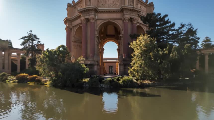 A camera pans out from an inside shot of a stone dome flanked by stone corridors with the people inside moving almost too fast to see as the camera pulls back to reveal the full glory of the architecture as well as trees and a rippling body of water