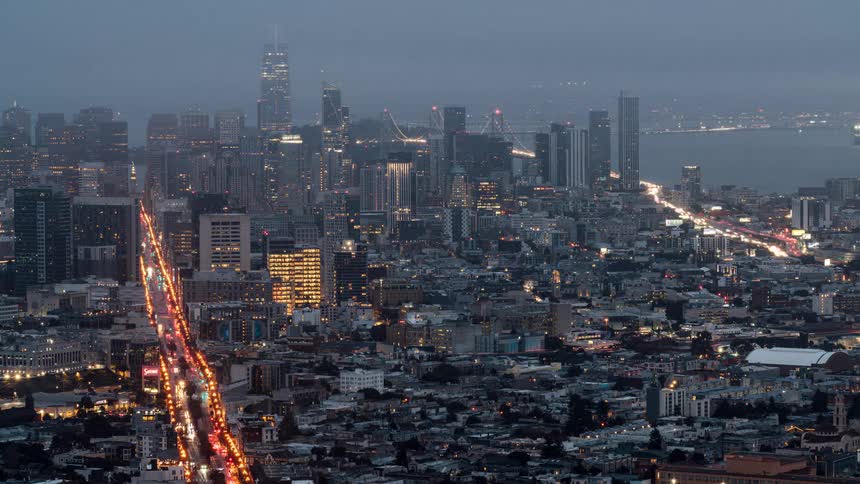 Traffic flowing all through the night as fog rolls in over the city