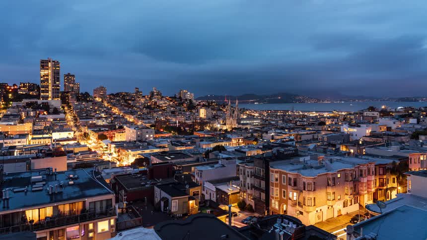 A day to night transition over a cityscape showcasing the gradual illumination of buildings and streets as darkness falls