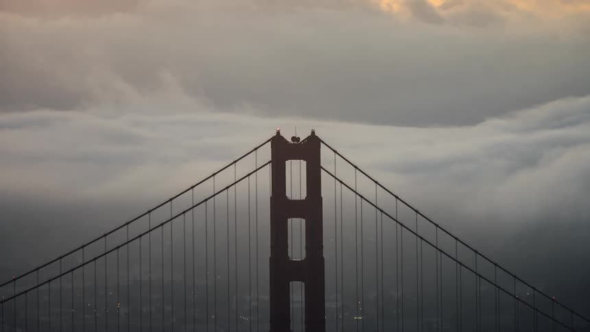 The silhouette of a bridge tower against a cloudy sky