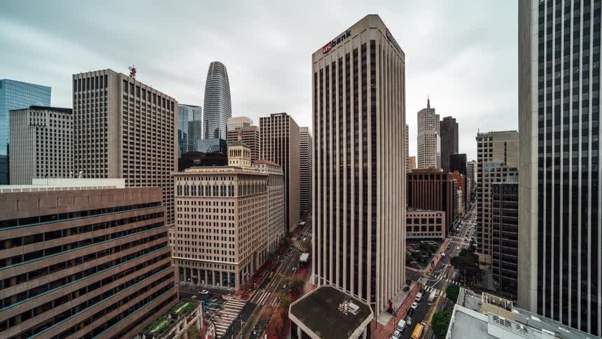 Aerial view of a busy city street lined with tall buildings including one prominently labeledus bank on its facade