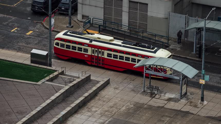 The red and white bus is driving around the block