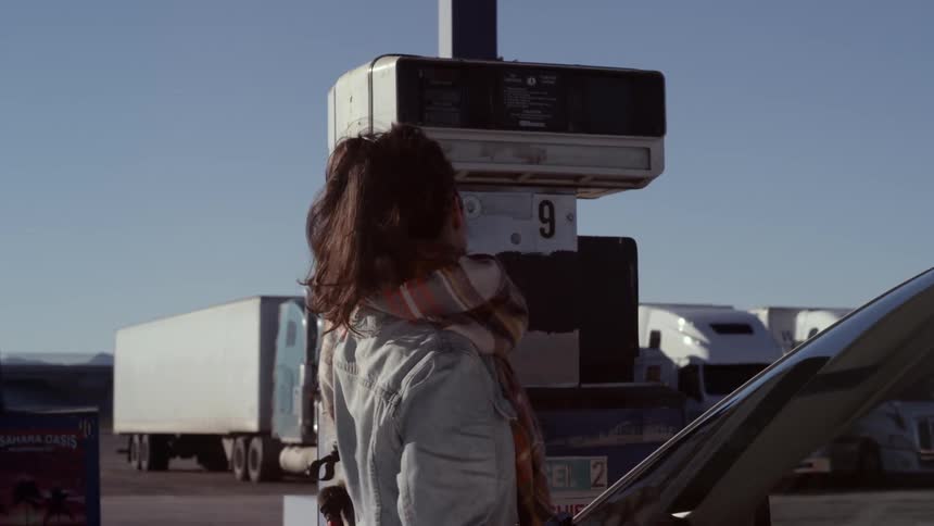 A young woman shows frustration before putting gasoline in her car