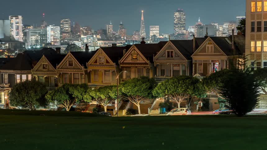 Traffic travels past a row of houses near downtown as night falls