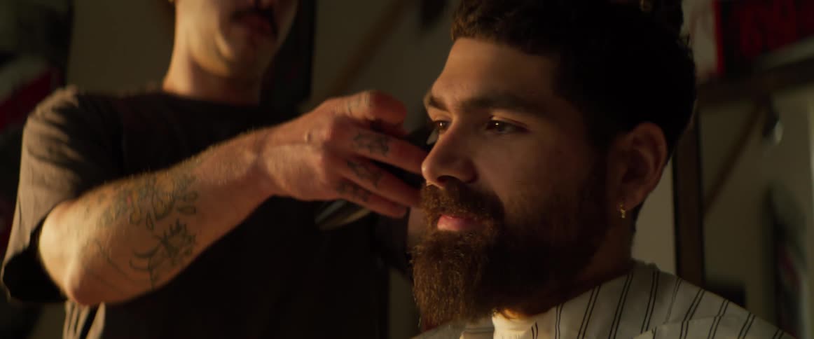 A man is using a razor to give the customer a haircut