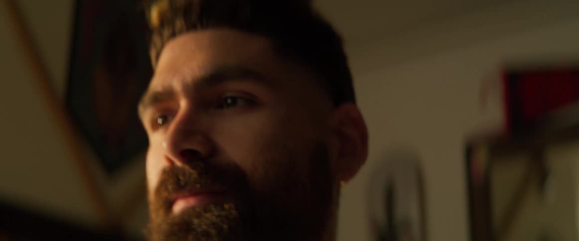 A man with a beard is standing alone inside of his room