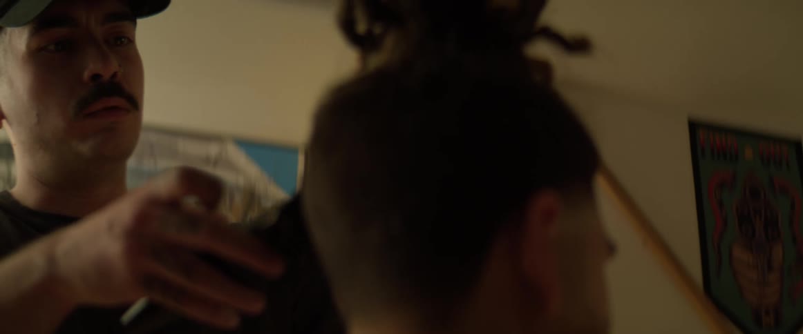 Closeup of a barber trimming a haircut with a razor blade in a dimly lit room