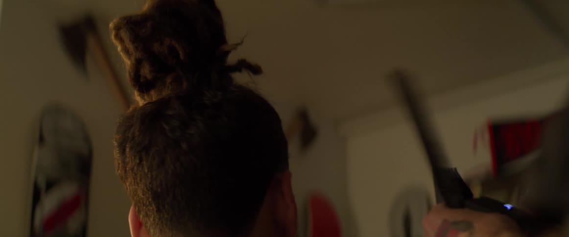 The barber holds the customers ear and shaves his hair