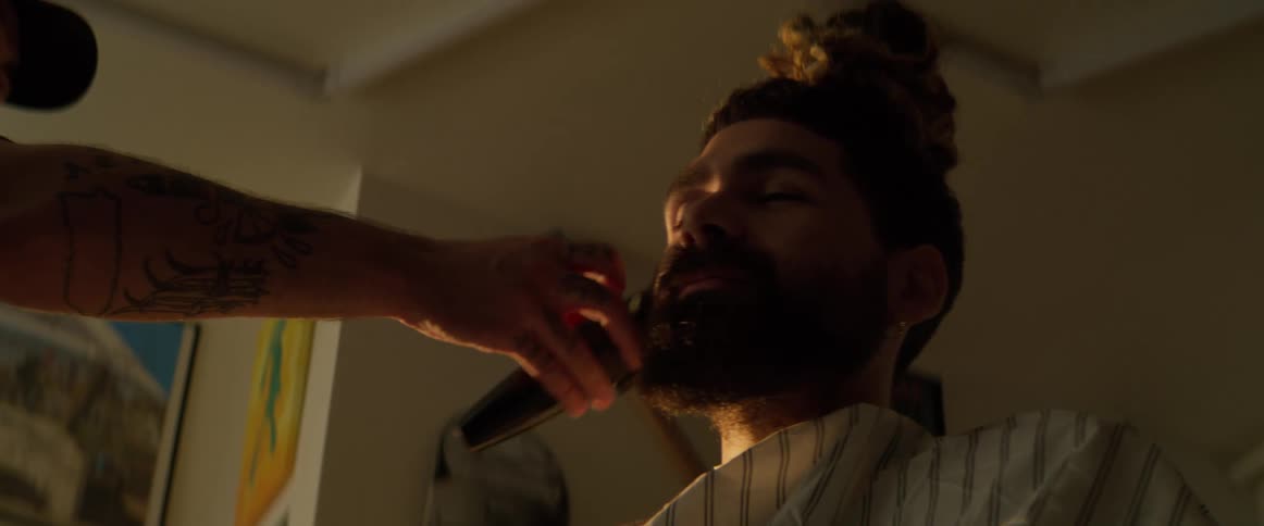 The customers beard is being trimmed at a barbershop