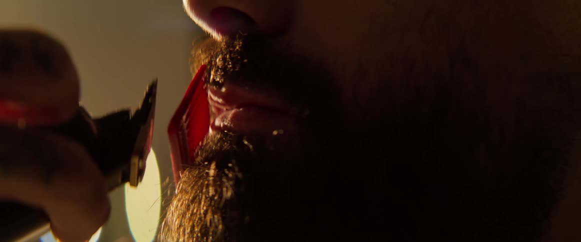 A mans beard is being cut by a barber