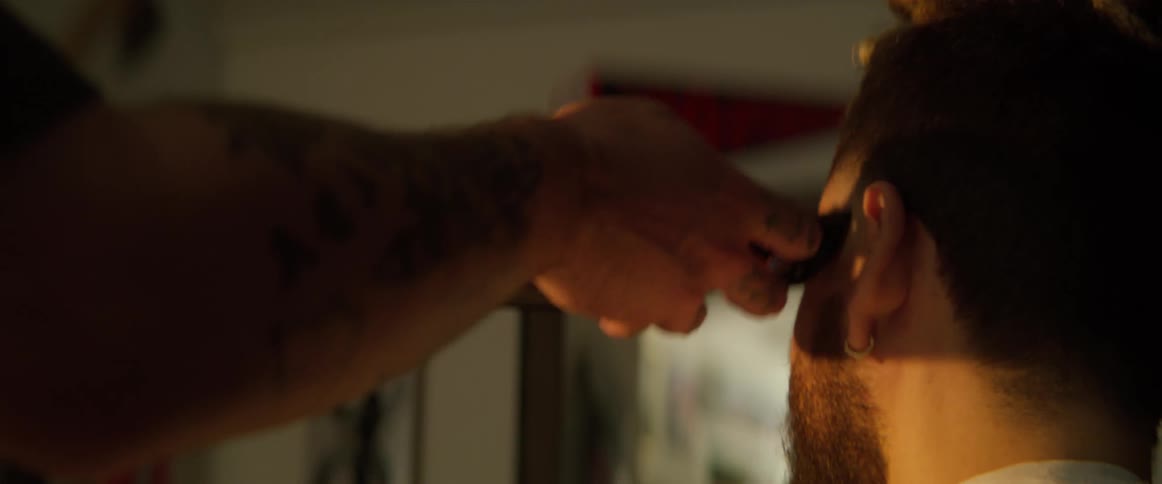 A closeup of a bearded man having his beard trimmed illuminated by warm sunlight