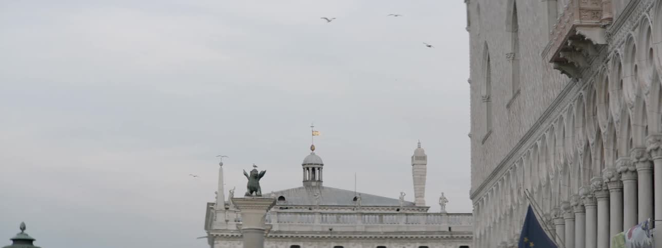 Birds fly across these buildings on a cloudy day