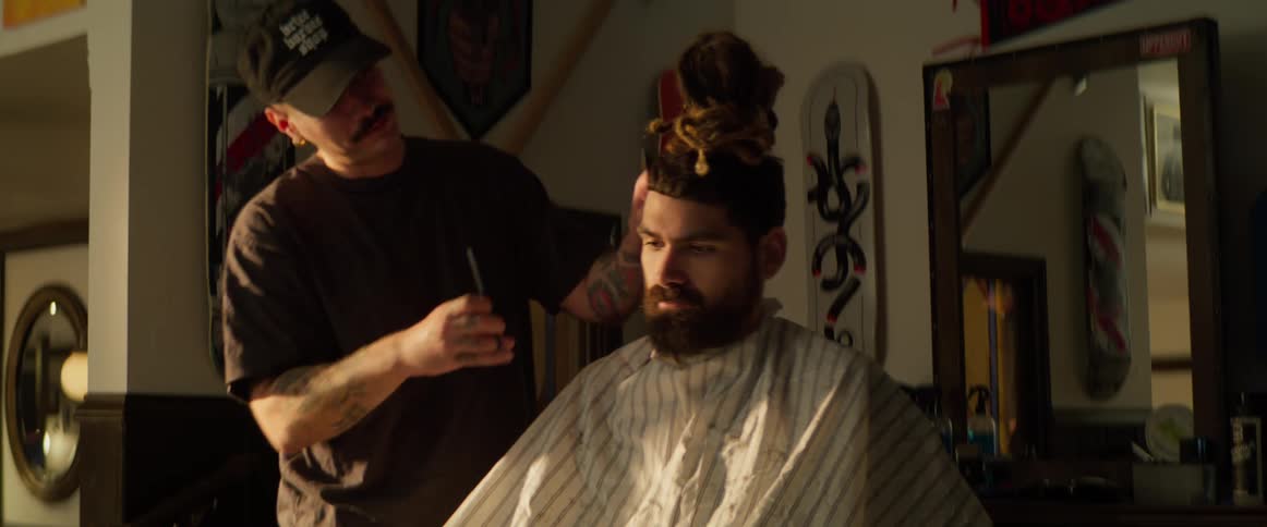 A barber is using a razor and comb to cut his hair