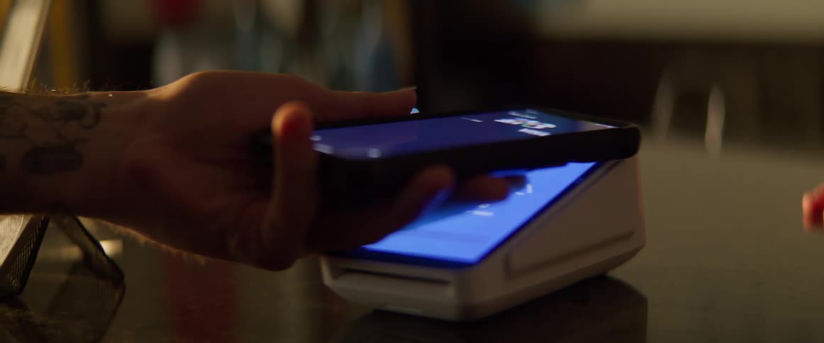 Man puts down a credit card machine to allow his male customer to pay with his smartphone
