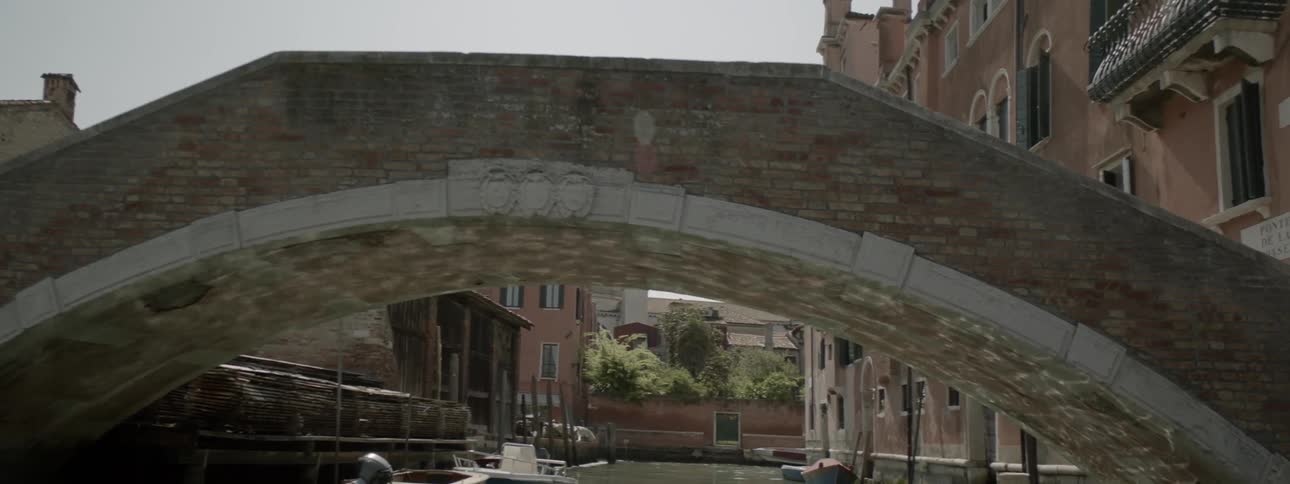 A boat floats under a canal bridge in a city
