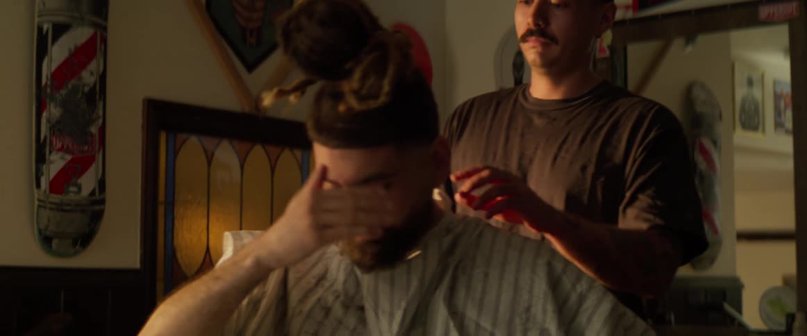 A barber removes the gown from a client