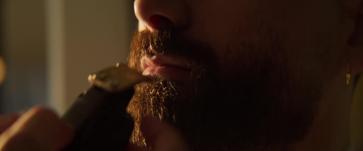 The barber trims the beard hair of a client