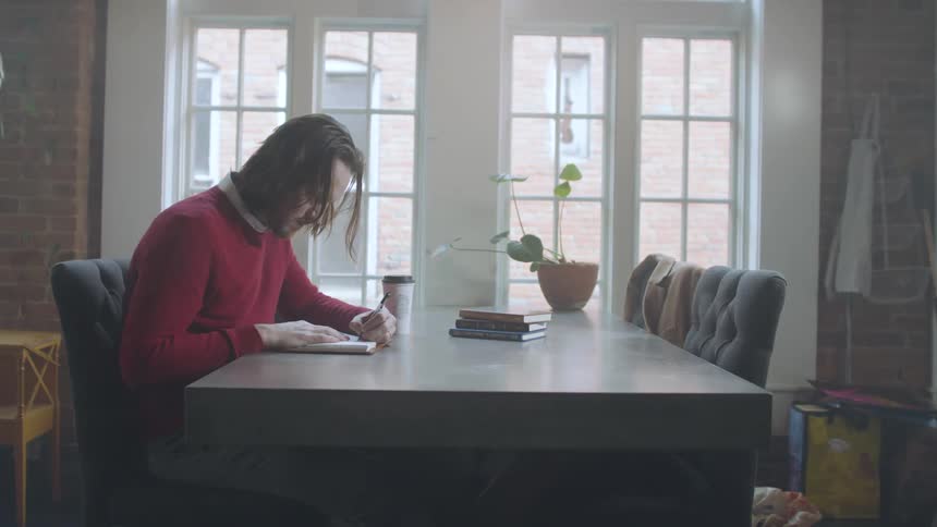 Boy writing on papers sitting at a table