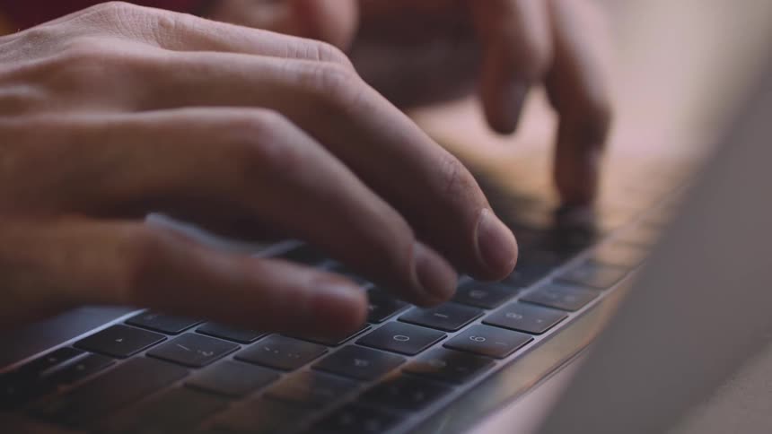 Hands typing on a computer keyboard