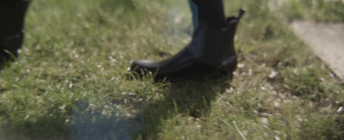 A person wearing boots walking across the grass