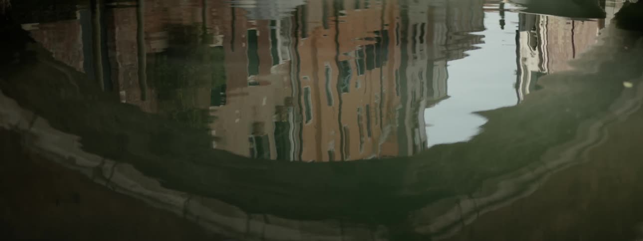Rippling water reflects a building