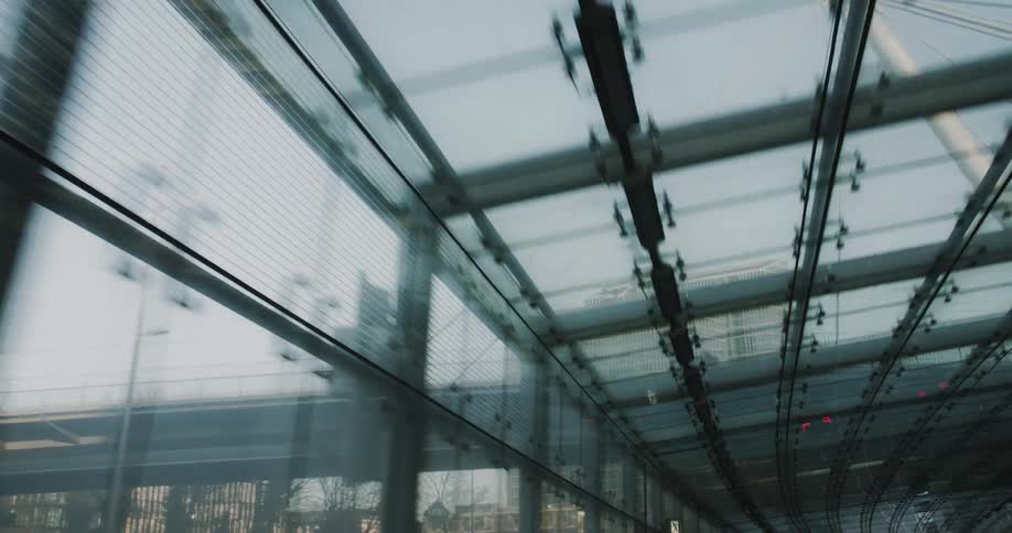 A subway path is enclosed with clear walls and ceiling in the city