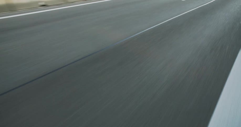 A gray asphalt road surface with white lines