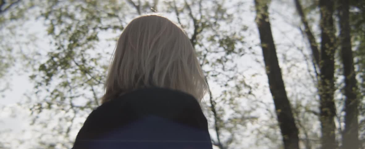A woman walking in a woods and looking down